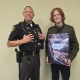 Fostoria News Police officer and young man holding a book together in an indoor setting.